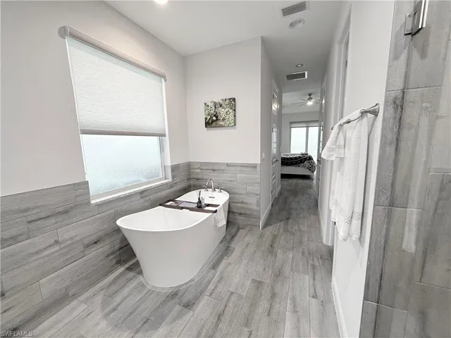 Bedroom featuring a tray ceiling, light wood-style flooring, and ceiling fan
