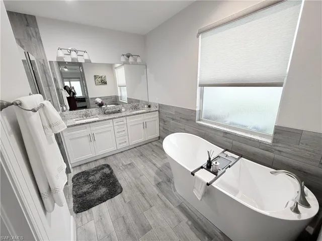 Bedroom with a raised ceiling, access to outside, light wood-style floors, and ceiling fan