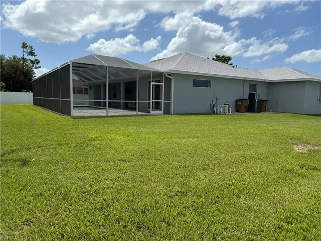 Back of property featuring stucco siding, a lanai, roof with shingles, and a pool