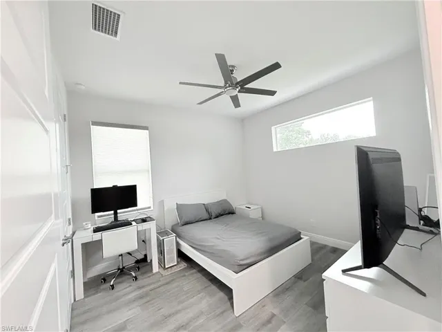 Bedroom with an office area, wood finished floors, and a ceiling fan