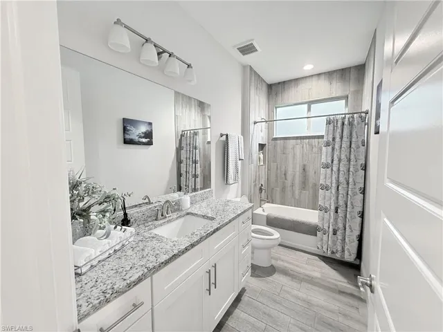 Bathroom featuring vanity, shower / bath combination with curtain, and recessed lighting