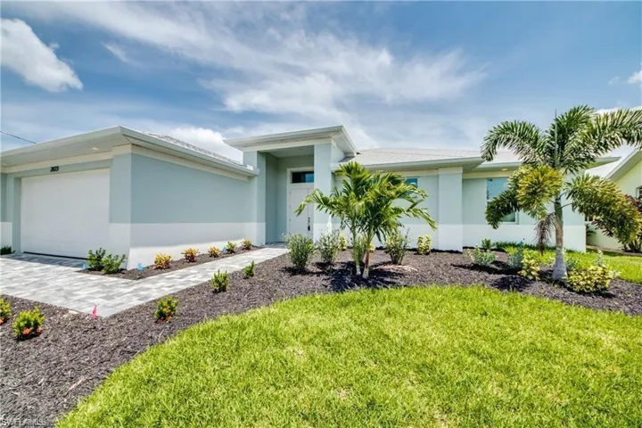 View of front of home featuring stucco siding, an attached garage, a front yard, and decorative driveway