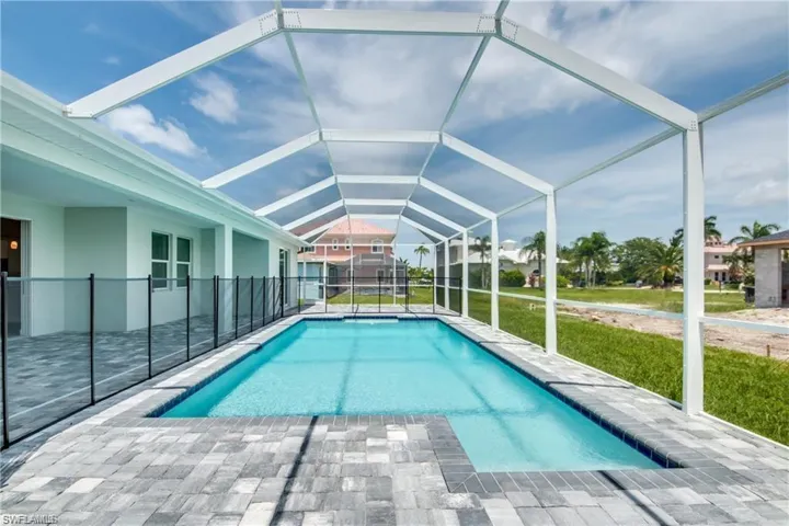 Swimming pool featuring a lanai, a lawn, and a patio area