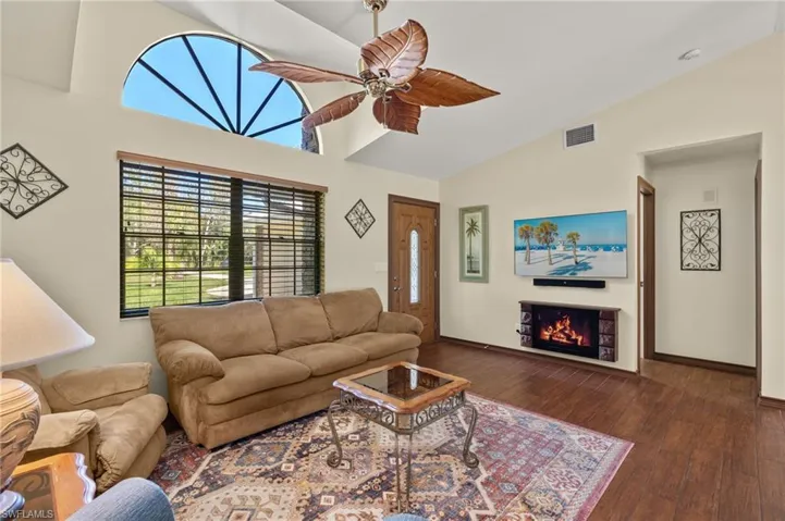 Living room featuring ceiling fan, dark wood-type flooring, and high vaulted ceiling