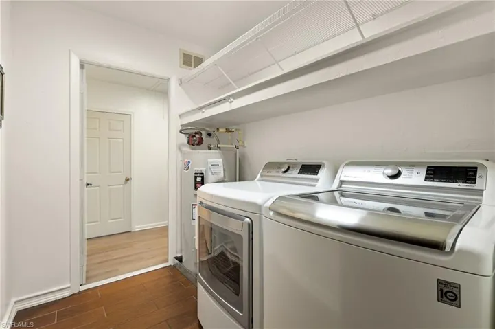 Laundry room featuring independent washer and dryer, dark hardwood / wood-style flooring, and electric water heater