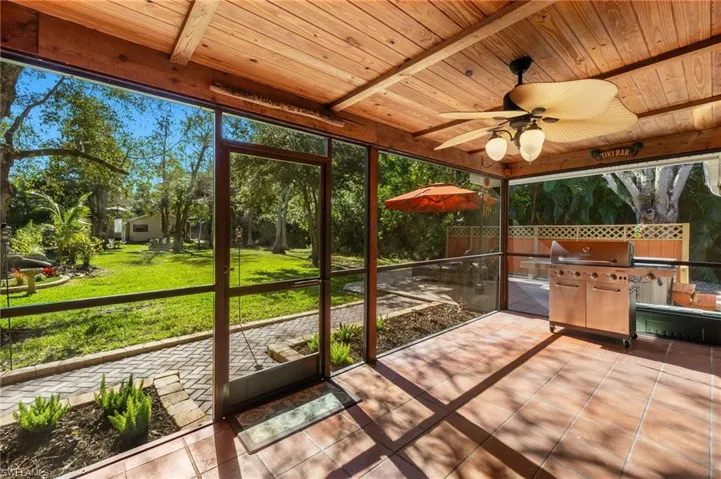 Sunroom with beam ceiling, ceiling fan, and wood ceiling