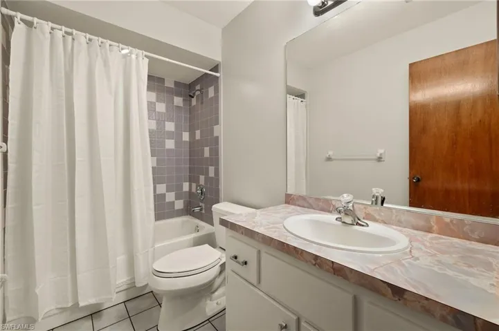Full bathroom with tile patterned flooring, shower / bath combination with curtain, vanity, and toilet