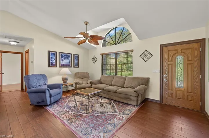 Living room featuring hardwood / wood-style floors, ceiling fan, and vaulted ceiling