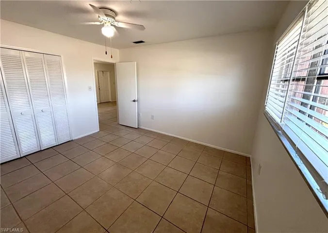 Unfurnished bedroom featuring tile patterned floors, a ceiling fan, and a closet