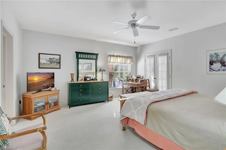 Carpeted bedroom with ceiling fan and french doors