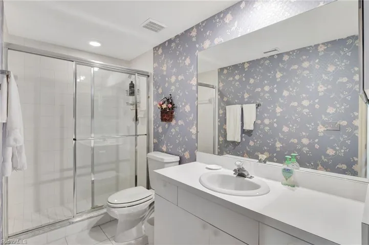 Bathroom with wallpapered walls, a stall shower, vanity, tile patterned flooring, and recessed lighting