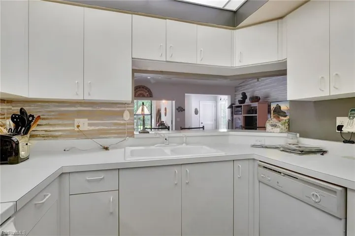 Kitchen with light countertops, white dishwasher, and white cabinetry