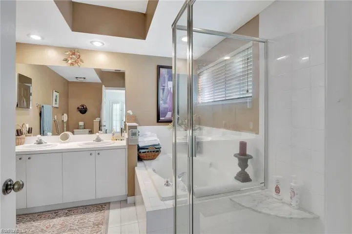 Bathroom featuring a stall shower, double vanity, tile patterned floors, and a garden tub