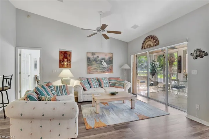 Living room featuring light wood-type flooring, a ceiling fan, and high vaulted ceiling