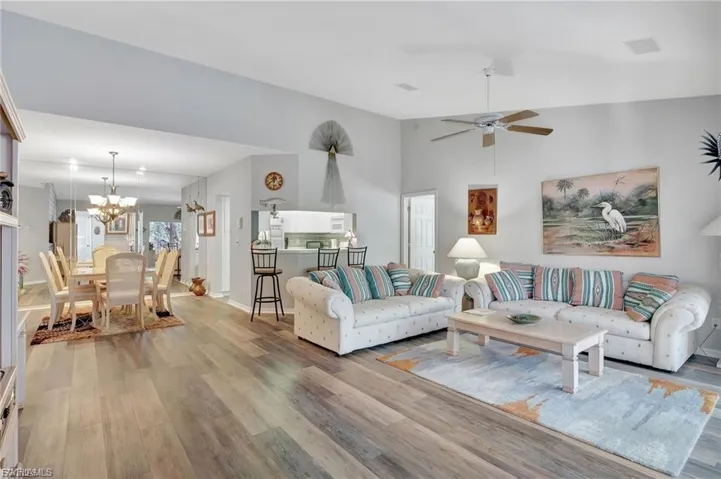 Living area featuring light wood-type flooring, a chandelier, and a ceiling fan