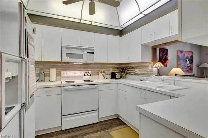 Kitchen featuring white appliances, white cabinets, light countertops, and ceiling fan