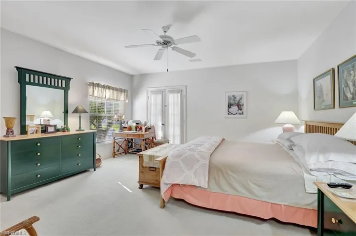 Bedroom featuring light carpet, an office area, and a ceiling fan