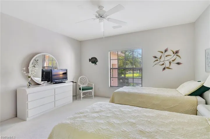 Bedroom with light colored carpet, multiple windows, and a ceiling fan