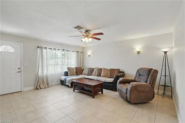 Living area featuring light tile patterned flooring and ceiling fan