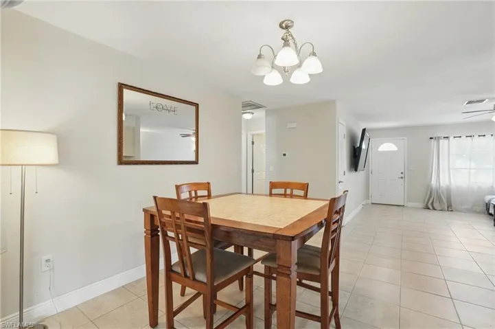 Dining space with a chandelier, light tile patterned floors, and ceiling fan