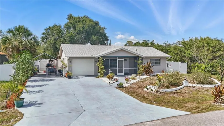 Ranch-style home with concrete driveway, a gate, a sunroom, a garage, and stucco siding