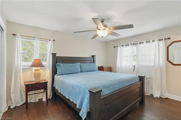 Bedroom with multiple windows, dark wood finished floors, and a ceiling fan