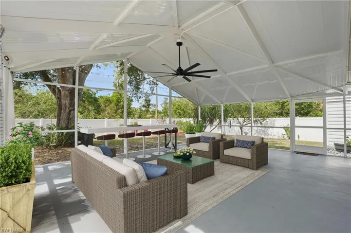 Fenced backyard with a sunroom, a ceiling fan, an outdoor living space, and a lanai