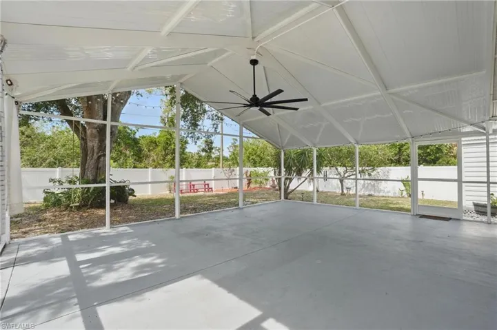 Unfurnished sunroom with vaulted ceiling, a ceiling fan, and a patio