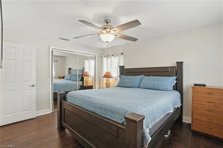 Bedroom with dark wood-style flooring, a closet, and a ceiling fan