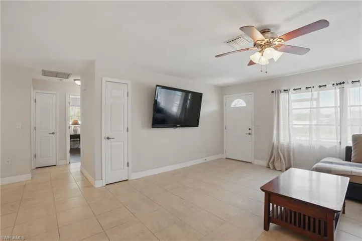 Living area with a ceiling fan and light tile patterned flooring