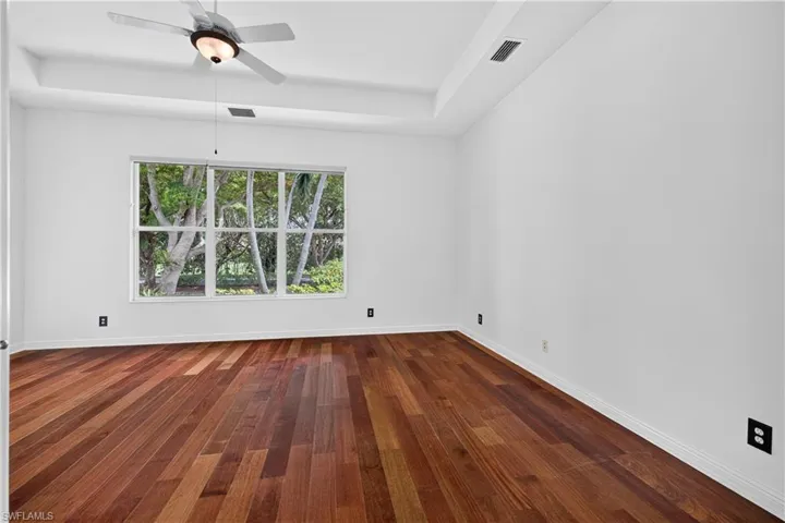 Wood-finish flooring, white walls, and a large multi-pane window