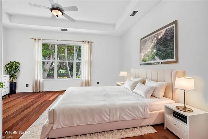 Virtual Staging Tray ceiling with a ceiling fan, wood flooring, and a large window