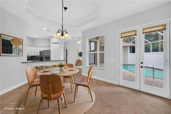 Virtual staging ideas Tray ceiling, tiled flooring, French doors with pool access, kitchen pass-through with stone countertop, and pendant lighting