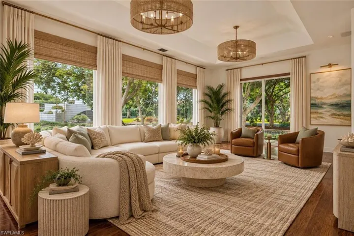 Sunlit living room showcasing multiple large windows with natural light, wood flooring, and a geometric area rug