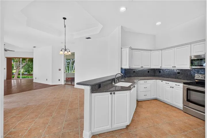Spacious kitchen featuring white cabinetry, stainless steel double wall ovens, dark countertops, and a centered island with prep space, Open floor Plan