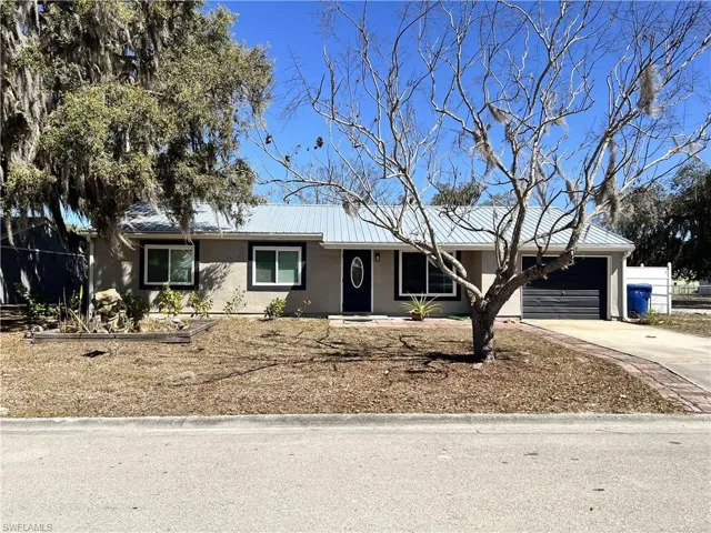 Single story home with driveway, stucco siding, a garage, and a metal roof