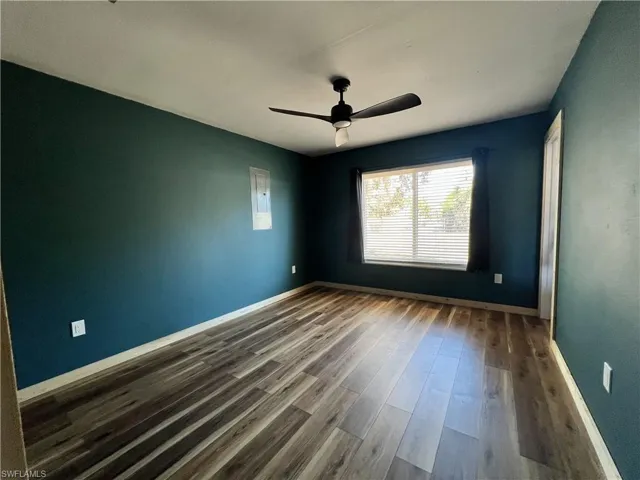 Unfurnished room with dark wood-type flooring, a ceiling fan, and electric panel