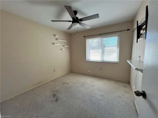 Carpeted spare room with a ceiling fan and baseboards