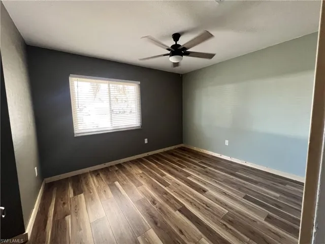 Empty room featuring dark wood-style floors and ceiling fan