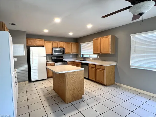 Kitchen with stainless steel appliances, light countertops, a kitchen island, recessed lighting, and light tile patterned floors