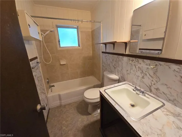 Full bathroom featuring vanity, tiled shower / bath combo, and toilet