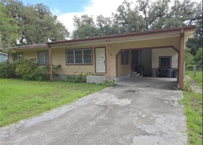 Ranch-style home featuring a carport and a front lawn