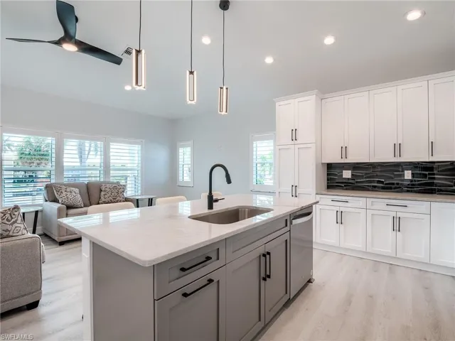 Kitchen with light hardwood / wood-style flooring, an island with sink, decorative light fixtures, a healthy amount of sunlight, and sink