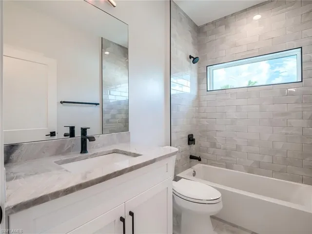 Full bathroom featuring tile floors, vanity, toilet, and tiled shower / bath combo