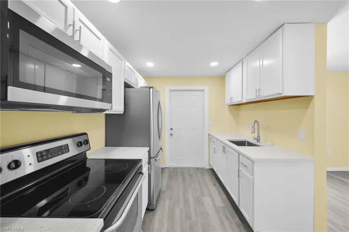 Kitchen featuring stainless steel appliances, white cabinets, light wood finished floors, and recessed lighting