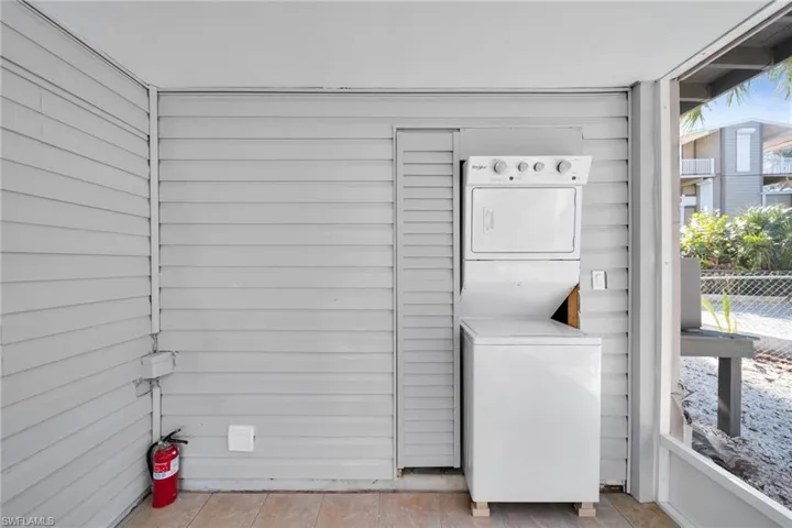 Laundry area with stacked washer / drying machine and wood walls