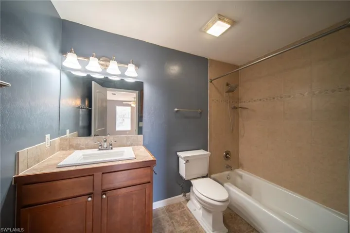 Bathroom featuring vanity,  shower combination, dark tile patterned floors, and a textured wall