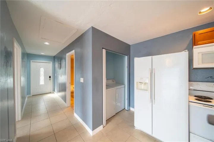 Kitchen featuring white appliances, independent washer and dryer, recessed lighting, light countertops, and light tile patterned floors