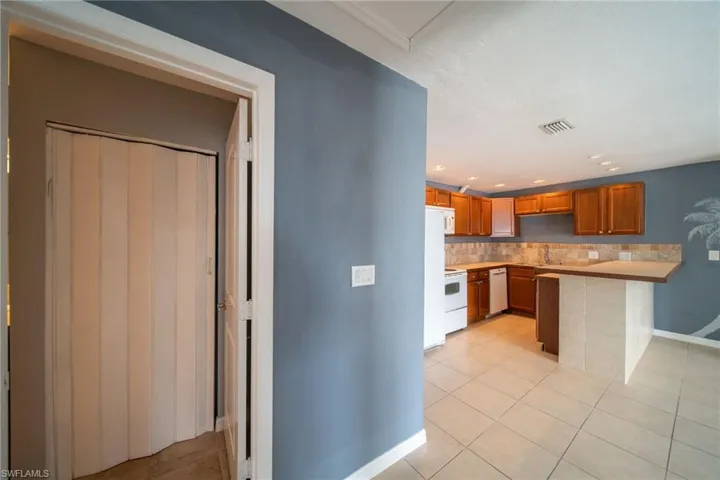 Kitchen featuring a peninsula, wood finish cabinets, light countertops, light tile patterned flooring, and recessed lighting