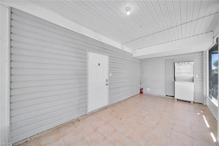 Unfurnished sunroom featuring stacked washer and clothes dryer